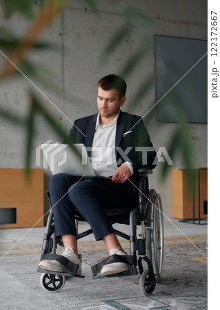 A director in a suit sitting in a wheelchair, using a ball in a modern office, embodying adaptability, focus, and leadership while navigating challenges in the workplace 122172667