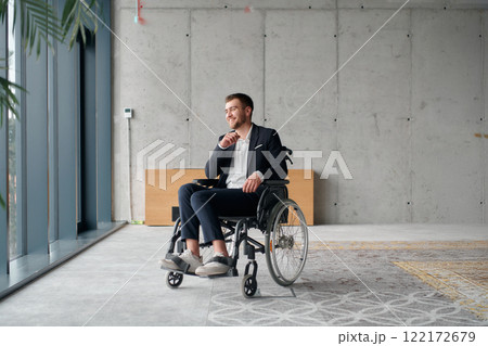 A director in a wheelchair sitting alone in an empty office, deeply reflecting on business strategies and decisions, contemplating the path forward with focused determination. 122172679