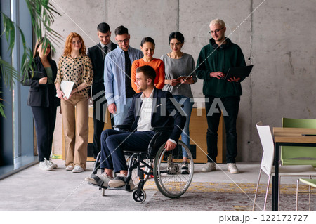 Multiethnic Business Team Collaborating in a Modern Office with Director in a Wheelchair Multiethnic Business Team Collaborating in a Modern Office with Director in a Wheelchair 122172727