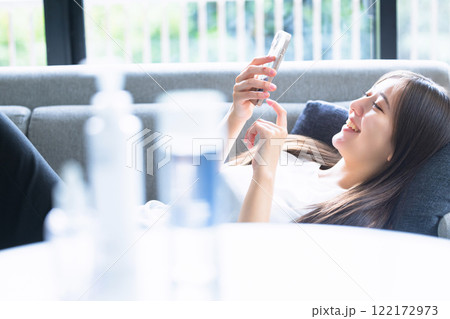 ソファーで寝転んでスマホを使う女性 ソファーで寝転んでスマホを使う女性 122172973