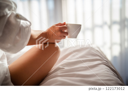 Woman with cup of coffee in the morning under the blanket at home Woman with cup of coffee in the morning under the blanket at home 122173012