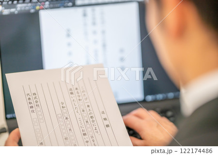 見本を見ながら退職届を作成する男性社員 見本を見ながら退職届を作成する男性社員 122174486