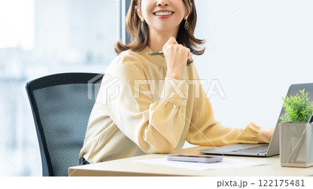 デスクワークをする笑顔の女性・ビジネスウーマン デスクワークをする笑顔の女性・ビジネスウーマン 122175481