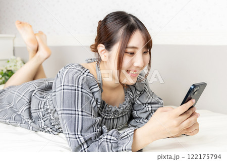 部屋でスマートフォンを持って寛ぐ女性 部屋でスマートフォンを持って寛ぐ女性 122175794