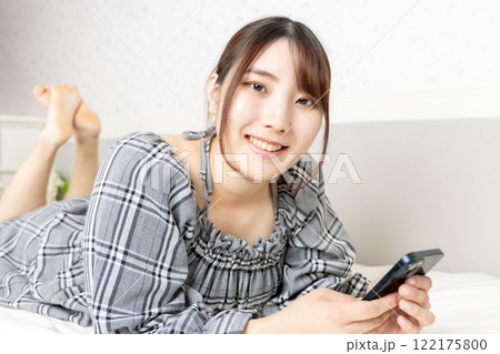 部屋でスマートフォンを持って寛ぐ女性 122175800