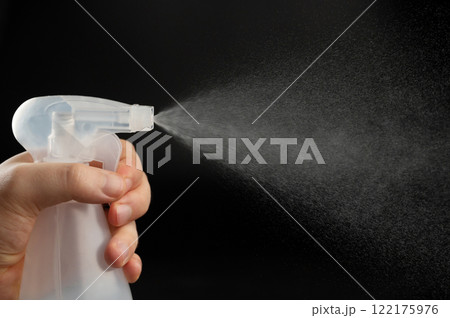 Close up of bottle in hand with spray cloud 122175976