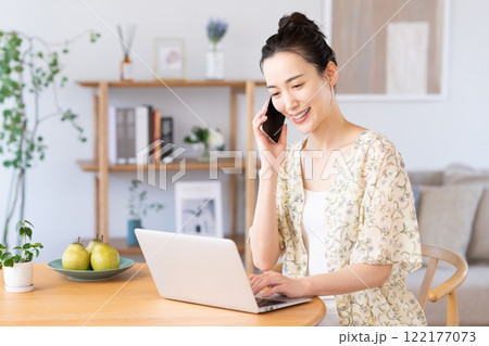 パソコンを使いながら電話をする若い女性 パソコンを使いながら電話をする若い女性 122177073