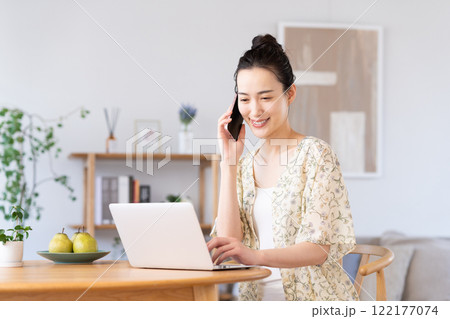 パソコンを使いながら電話をする若い女性 パソコンを使いながら電話をする若い女性 122177074