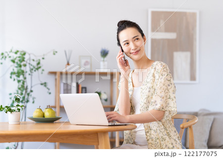 パソコンを使いながら電話をする若い女性 パソコンを使いながら電話をする若い女性 122177075