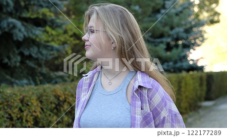 A blonde girl wearing glasses and a relaxed expression poses in a tranquil outdoor setting. This image reflects authenticity and the quiet charm of everyday moments. A blonde girl wearing glasses and a relaxed expression poses in a tranquil outdoor setting. This image reflects authenticity and the quiet charm of everyday moments. 122177289