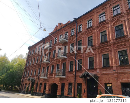 An ornate red brick facade with symmetrical windows, decorative balconies, and carved patterns. The photo captures the beauty and richness of historic architecture in a modern urban setting. An ornate red brick facade with symmetrical windows, decorative balconies, and carved patterns. The photo captures the beauty and richness of historic architecture in a modern urban setting. 122177313