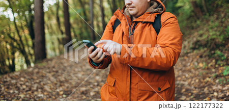 Young Caucasian 30s man backpacker with smartphone catching signal at wooden forest. Road trip, transport, travel, technology and people concept. High quality photo Young Caucasian 30s man backpacker with smartphone catching signal at wooden forest. Road trip, transport, travel, technology and people concept. High quality photo 122177322