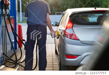 Fueling a car at a gas station during sunset light. 122177757