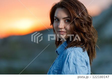 Young woman smiles at sunset while standing outdoors in nature 122180147
