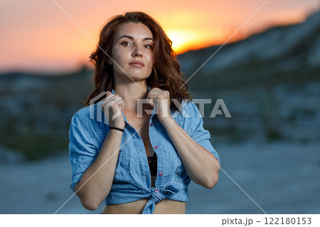 Woman posing confidently at sunset by a sandy landscape Woman posing confidently at sunset by a sandy landscape 122180153