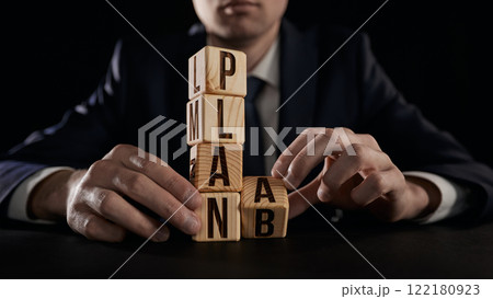 The hand turns the wooden cube and can't decide whether to change PLAN A to PLAN B. 122180923