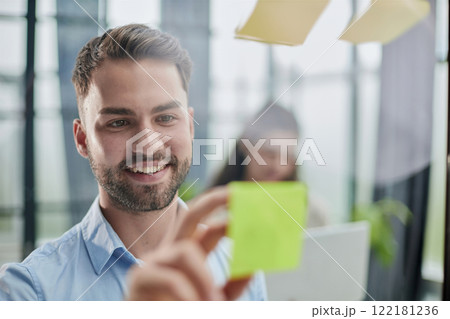 businessman is working on a project. Business man pointing at a note on the glass wall in the office. businessman is working on a project. Business man pointing at a note on the glass wall in the office. 122181236