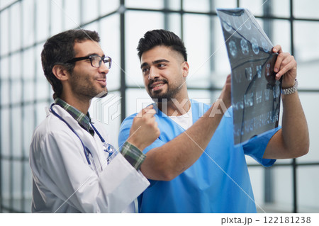 Male medics consult with each other while looking at x ray image. 122181238