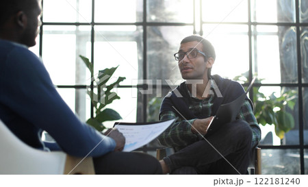 Thoughtful business man in formalwear holding paper while sitting at chair fills out a resume questionnaire in office Thoughtful business man in formalwear holding paper while sitting at chair fills out a resume questionnaire in office 122181240