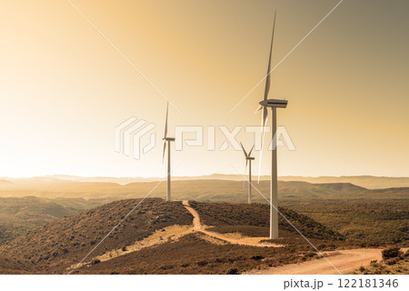Turbines in a mountain wind farm at sunset. Ecological energy production. 122181346