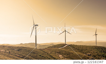 Turbines in a mountain wind farm at sunset. Ecological energy production. 122181347