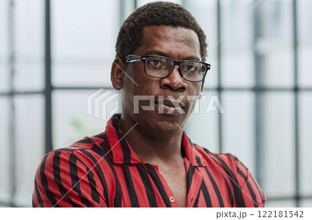 Portrait of confident african american businessman with glasses standing in office with crossed arms 122181542