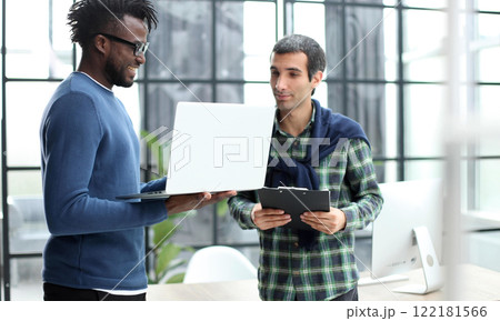 young business men standing together holding a laptop, discussing business 122181566