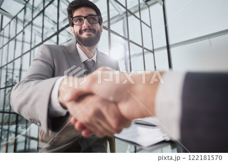 Handshake of two businessmen who enters into the contract to develop a new software to improve business service at a company. Handshake of two businessmen who enters into the contract to develop a new software to improve business service at a company. 122181570