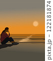 A woman sits on a sandy beach by the sea watching the sunset. 122181874