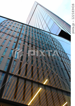 modern high-rise office building in the financial center of the city, wide angle view of a skyscraper with glass panoramic windows in the business district of the European capital during the day modern high-rise office building in the financial center of the city, wide angle view of a skyscraper with glass panoramic windows in the business district of the European capital during the day 122183416