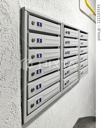 Gray mailboxes at the entrance of an apartment building, on a white background. Mail, mail items, correspondence, magazines, newspapers, and letters. Perspective image Gray mailboxes at the entrance of an apartment building, on a white background. Mail, mail items, correspondence, magazines, newspapers, and letters. Perspective image 122183543