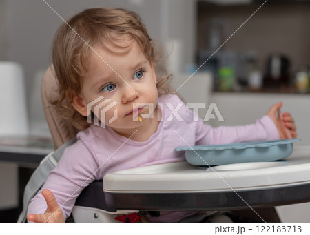 A curious toddler exploring their surroundings during a playful mealtime moment. 122183713