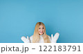 Winter portrait on blue background, happy blonde woman wearing warm mittens and knitted jumper, fashion and lifestyle idea 122183791