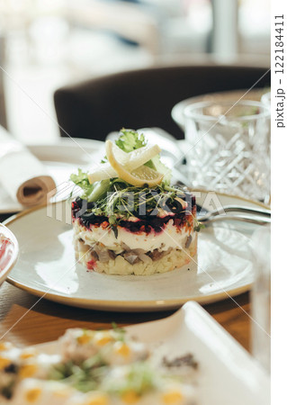 Dressed herring or herring under a fur coat. Traditional Russian cuisine. Layered salad composed of diced pickled herring covered with layers of boiled grated vegetables and mayonnaise. 122184411