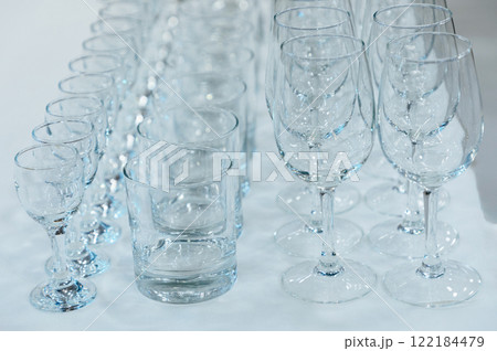 many different empty glass transparent glasses stand on the table in rows many different empty glass transparent glasses stand on the table in rows 122184479