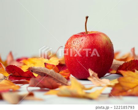 Bright red apple with autumn leaves on a gray surface, seasonal fruit, autumn 122185793