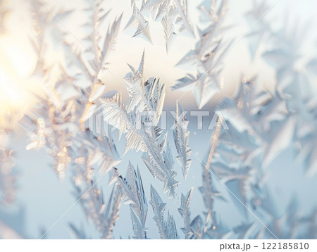 Close-up of intricate frost patterns on a window with soft sunlight in the background winter detail 122185810