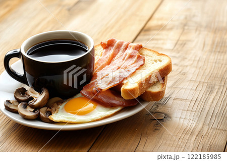 Delicious Breakfast Plate with Fried Egg, Bacon, Toast, Mushrooms, and Coffee on Wooden Table 122185985