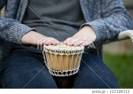 Closeup of hands playing a small djembe drum 122186152