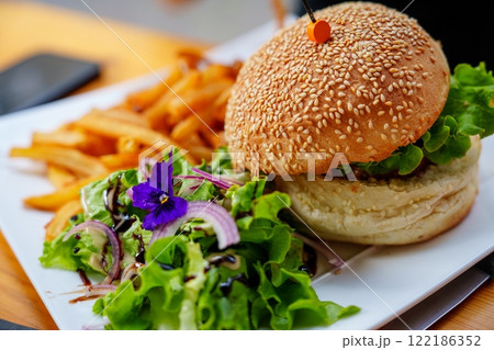 Delicious Gourmet Burger with Fresh Toppings and Crispy Golden Fries Served on a Beautiful Plate 122186352
