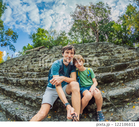 Father and son tourists exploring the ancient ruins of Coba, Mexico. Family bonding, cultural heritage, and adventure travel concept in the Yucatan Peninsula Father and son tourists exploring the ancient ruins of Coba, Mexico. Family bonding, cultural heritage, and adventure travel concept in the Yucatan Peninsula 122186811
