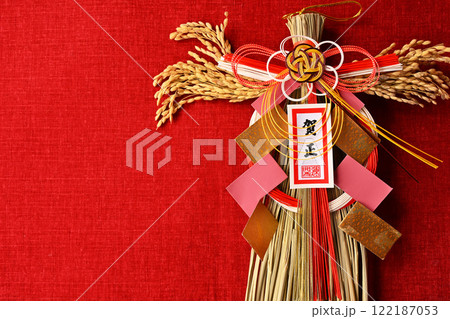 年始に飾るお正月飾り、稲穂付きで日本らしさあり。赤い布を背景に。 122187053