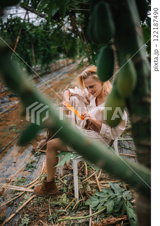 Woman harvesting fruits in a greenhouse surrounded by plants in the afternoon 122187490
