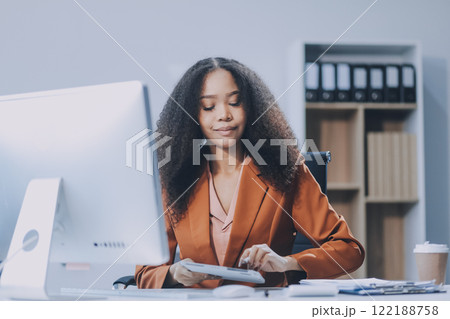 Young happy professional business woman employee sitting at desk working on laptop in modern corporate office interior. Smiling female worker using computer technology typing browsing web. 122188758