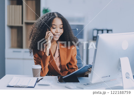Asian woman using smart phone and laptop in office. Asian woman using smart phone and laptop in office. 122188759