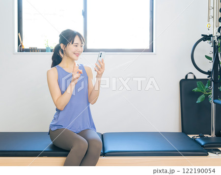 スポーツジムでスマホを使う女性 スポーツジムでスマホを使う女性 122190054