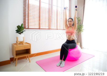 Young asian woman in sportswear workout with dumbbells for strength in living room at home. Young asian woman in sportswear workout with dumbbells for strength in living room at home. 122190219