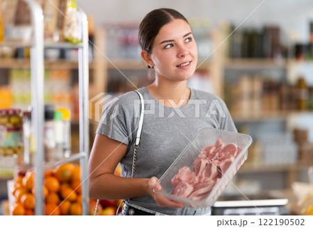 Young woman choosing lamb in grocery store 122190502