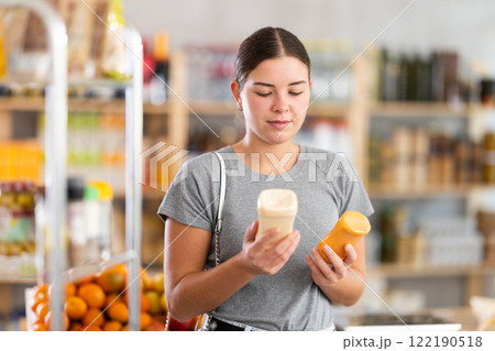 Young woman chooses mustard or mayonnaise sauces 122190518