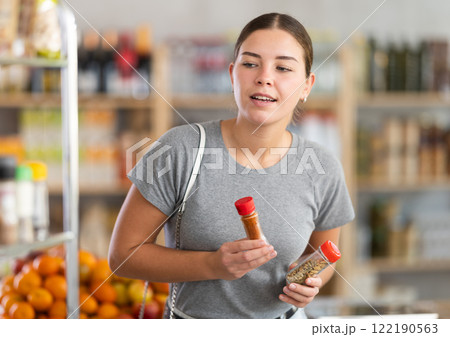 European youth girl choose and buy spices in store 122190563